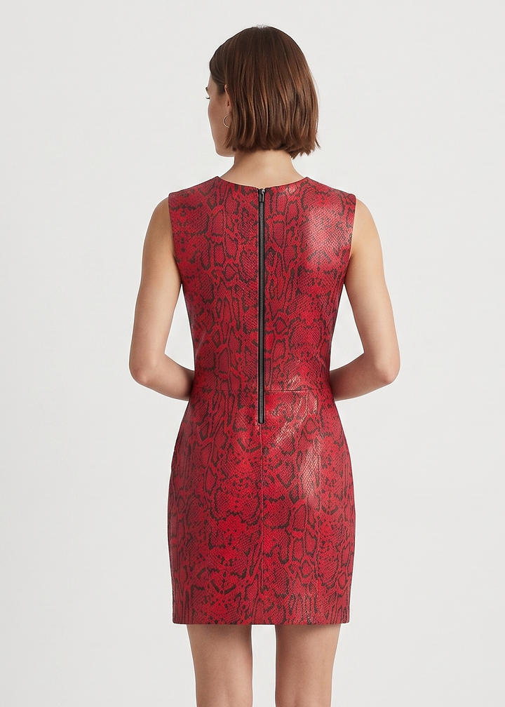 A woman viewed from the back wearing a sleeveless red dress with a black snakeskin-style pattern and a black center zipper, paired with black heels, against a plain light gray studio background.